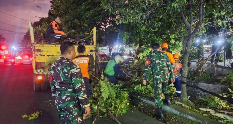 Babinsa Sawojajar Sigap Dampingi Evakuasi Ranting Pohon Tersangkut Kabel Listrik